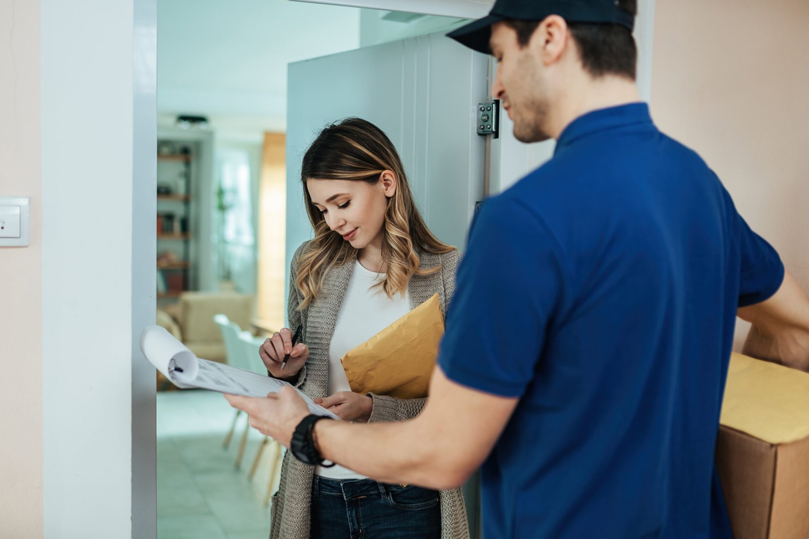 Young woman signing for home delivery to a courier.